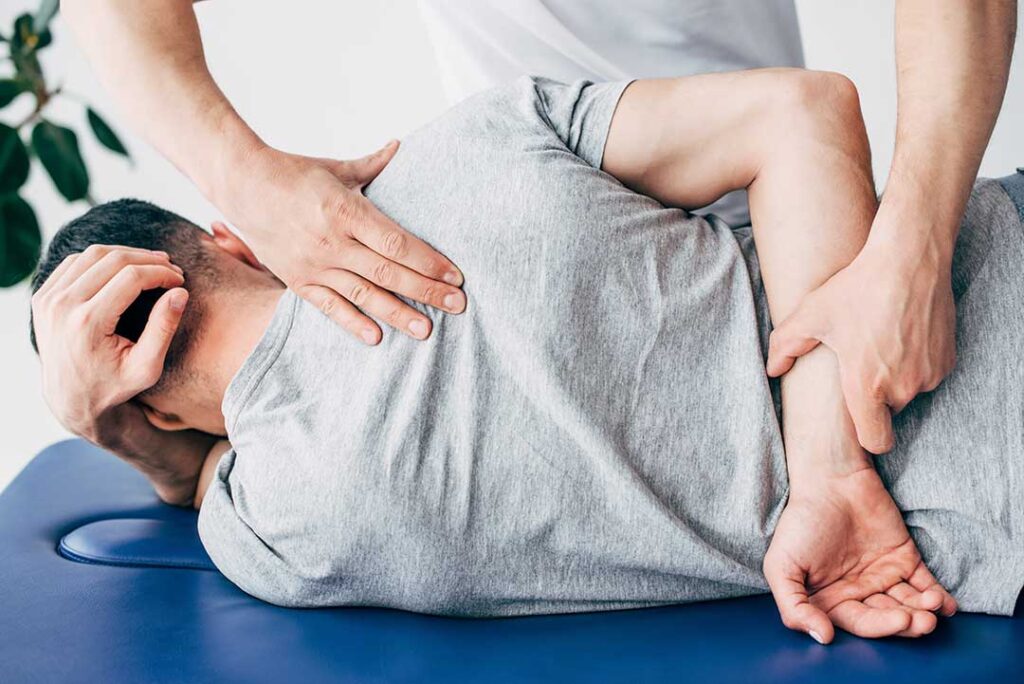 Person doing gentle knee stretches beside a chair with a warm towel and fresh vegetables nearby.