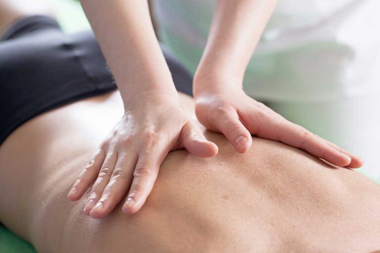 Person applying a warm compress to a mildly sore back after a chiropractic adjustment.
